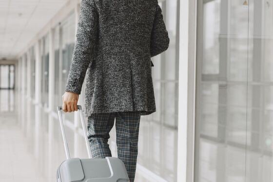Voyageur en costume traversant le hall d'un terminal avec sa valise